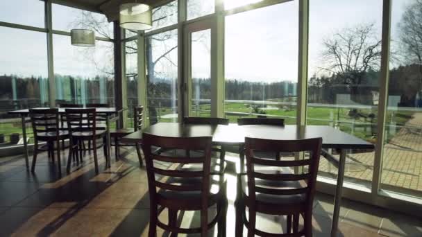 简单的乡村客栈餐厅室内餐厅 在高尔夫球场的窗口视图后面 夕阳西下 室内的桌子和椅子很简单 — 图库视频影像