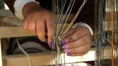 Loom Dokumaya Hazırlanan Kadın. İplikleri göz bebeklerinden geçiriyoruz. Dokuma bir tekstil üretim metodudur. Bir kumaş veya kumaş oluşturmak için iki iplik dizisi birbirine karışır..