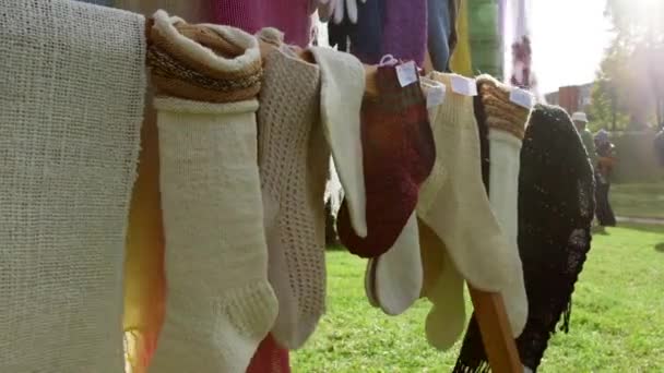 ニットソックス スカーフ グローブは 職人の市場でスタンドに掛かります 編み物は 同じまたは他のヤーンのループでヤーンループを交換することによって織物の生産のための方法です — ストック動画