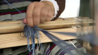 Loom 'da Mavi Jartiyer Ören Kadın. Dokuma bir tekstil üretim metodudur. Bir kumaş veya kumaş oluşturmak için iki iplik dizisi birbirine karışır..