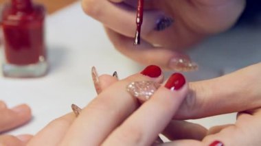 Manikürcü müşterilere Parlak Kırmızı Cila uyguluyor. Manikür, evde ya da manikürcüde yapılan çoğunlukla kozmetik güzellik tedavisidir..