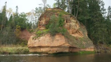 Üzerinde ağaçlar olan Vahşi Orman Nehri 'nin kıyısındaki büyük, kırmızı kumtaşı çıkıntısı. 19 metre yüksekliğindeki Zvarte Kayası Letonya 'nın en popüler ve manzaralı kum taşı çıkışlarından biridir..