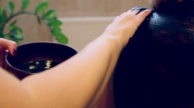 Masör, Kara Çamur 'u kadının omzuna ve sırtına nazikçe bastırır. Çamur Masajları Biostimülasyon Özellikleri Hasarlı Cildin Yenilenmesini Destekliyor ve Alerji Semptomlarını Rahatlatıyor.