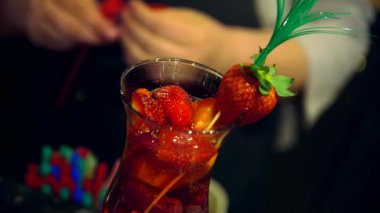 Garson, kırmızı plastik çubuğu limonata bardağına çilekli kokteyl koyuyor. Anne babasıyla güzel bir restoranı ziyaret eden her çocuğa limonata iyi gelir..