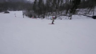 Çocuk tepeden aşağı kaymayı öğreniyor. Geniş Virajlar ve İnce Virajlar Yapıyor. Küçük bir tepeden başlayarak kayak yapmayı öğrenebilirsin. Öğrenilecek ilk şey nasıl durdurulacağını olmalı..