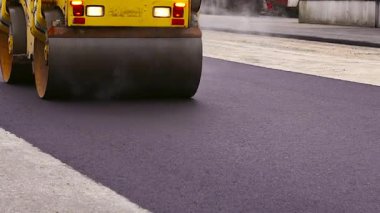 Asfalt Paving. Road Roller Sıcak, Buharlı, Taze Asfalt Üzerinde Sürüyor. Road Roller, Paten sıkıştırıcı veya paten sıkıştırıcı, asfalt sıkıştırmak için kullanılan bir sıkıştırma tipi mühendislik aracıdır..