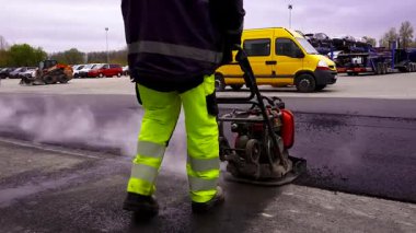 İşçi, asfalt titreşim plaka sıkıştırma makinesiyle çalışır. Yol Yapımı Projelerinin İstikrar ve Uzun Yaşamını Sağlamak için Sıkıştırma Ekipmanı Hayati önem taşıyor.