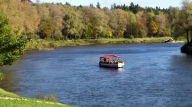 Küçük Renkli Turist Teknesi - Raft, Sonbaharda nehir boyunca yelken açıyor. Valmiera, Hanseatik Birliği üyesi olarak Letonya 'nın en eski şehirlerinden biridir..