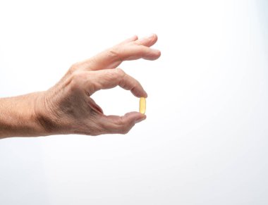 E vitamini yumuşak jel kapsülü. Beyaz arka planda el ele tutuşma hapı.
