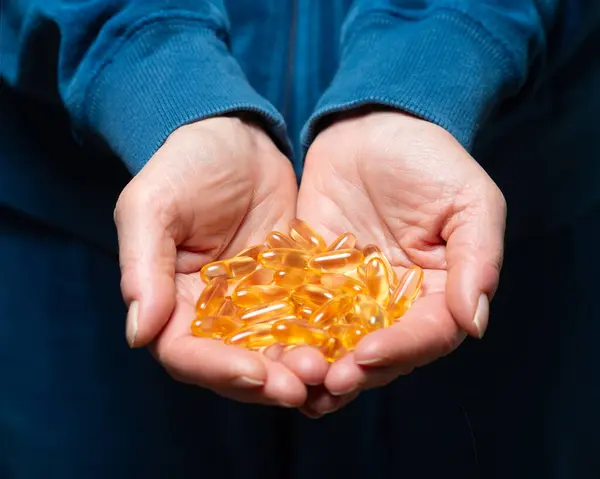 Ellerinde E vitamini yumuşak jel kapsülleri var..
