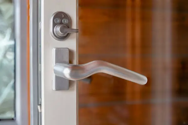 Metal kapı kolu ve beyaz çerçeveli cam kapıya kilitlenir..