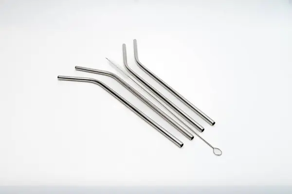 Beyaz arka planda metalik pipetler ve temizlik fırçası..
