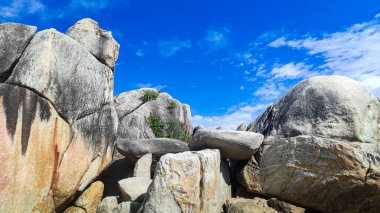 Sahildeki parlak mavi gökyüzü arka planına sahip doğal granit taş yığınının görüntüsü
