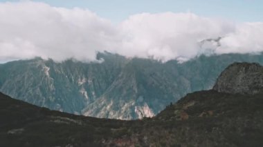 İnsansız hava aracı, arka plandaki dağlarla bir uçurumdan aşağı uçuyor ve Curral das Freiras, Madeira şehrini gözler önüne seriyor.