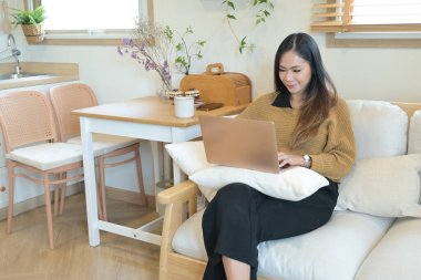 Önünde dizüstü bilgisayarı olan bir kadın koltukta oturuyor..