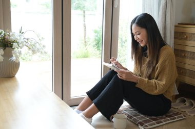 Önünde bir not defteriyle yerde oturan bir kadın. Gülümsüyor ve eğleniyor...