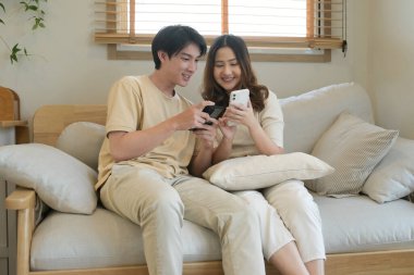 Bir adam ve bir kadın koltukta oturuyor, ikisi de cep telefonlarına bakıyor...