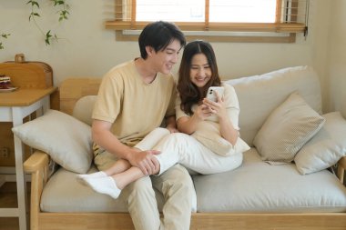 Bir adam ve bir kadın koltukta oturuyor, ikisi de cep telefonlarına bakıyor...