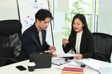 Çalışma masasında bilgisayar ve dijital tabletle birlikte çalışan genç ofis çalışanlarının fotoğrafı...