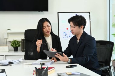 Çalışma masasında bilgisayar ve dijital tabletle birlikte çalışan genç ofis çalışanlarının fotoğrafı...