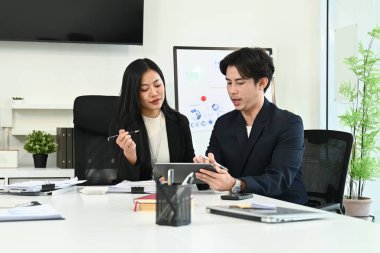 Çalışma masasında bilgisayar ve dijital tabletle birlikte çalışan genç ofis çalışanlarının fotoğrafı...