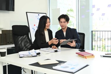 Çalışma masasında bilgisayar ve dijital tabletle birlikte çalışan genç ofis çalışanlarının fotoğrafı...