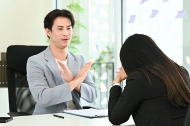 Bir adam ve bir kadın masada oturuyorlar. Adam kadının önünde elini sıkıyor..