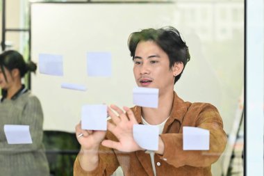 Bir adam beyaz kağıtla pencereye resim çiziyor. O gülümsüyor ve eğleniyor gibi görünüyor. Yaratıcılık ve eğlence kavramı. Çünkü adam pencereyi sanat eserleri için bir tuval olarak kullanıyor...