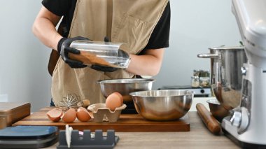 Bir kişi pasta yapıyor ve ona baharat ekliyor. Baharatlar metal bir kaba dökülüyor...