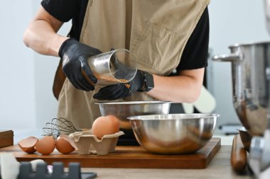 Bir kişi pasta yapıyor ve ona baharat ekliyor. Baharatlar metal bir kaba dökülüyor...