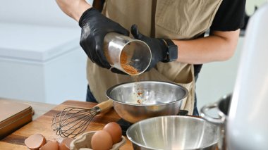 Bir kişi pasta yapıyor ve ona baharat ekliyor. Baharatlar metal bir kaba dökülüyor..