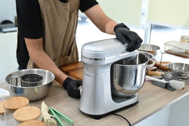 Mutfakta bir kişi pasta yapıyor. Siyah önlük ve eldiven giyiyor. Pasta hamuru önce karıştırma kabına sonra da miksere dökülüyor...