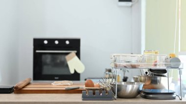 Üzerinde beyaz fırın eldiveni olan siyah bir fırın. Fırın ocağın yanındaki tezgahın üstünde...