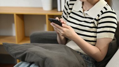 Bir kadın kanepede oturuyor ve cep telefonunu kullanıyor..