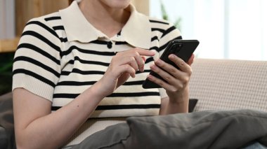 Bir kadın kanepede oturuyor ve cep telefonunu kullanıyor...