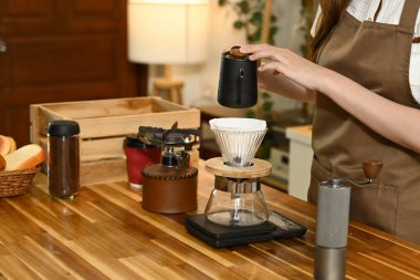 Bir kadın kahve yapıyor ve fincana döküyor. Sahne, bir terazi, bir bardak, bir şişe ve bir kase gibi çeşitli malzemelerle bir mutfakta geçiyor. Kadın önlük giyiyor...