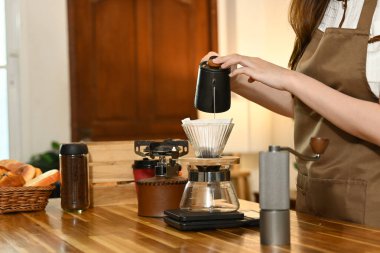 Bir kadın kahve yapıyor ve fincana döküyor. Sahne, bir terazi, bir bardak, bir şişe ve bir kase gibi çeşitli malzemelerle bir mutfakta geçiyor. Kadın önlük giyiyor...