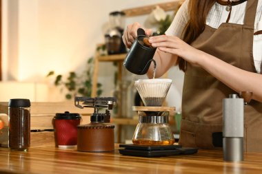 Bir kadın kahve yapıyor ve fincana döküyor. Sahne, bir terazi, bir bardak, bir şişe ve bir kase gibi çeşitli malzemelerle bir mutfakta geçiyor. Kadın önlük giyiyor..