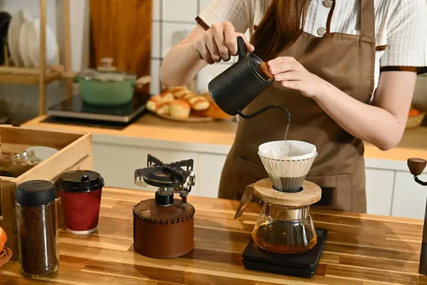 Bir kadın kahve yapıyor ve fincana döküyor. Sahne, bir terazi, bir bardak, bir şişe ve bir kase gibi çeşitli malzemelerle bir mutfakta geçiyor. Kadın önlük giyiyor...