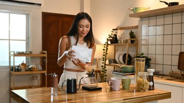 Bir kadın mutfakta kahve yapıyor. Mutfak çeşitli malzemelerle dolu..