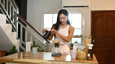 Bir kadın kahve yapıyor. Kahveyi fincana dökerken gülümsüyor...