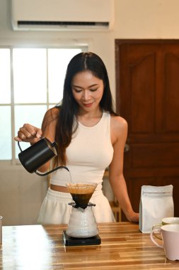 Bir kadın kahve yapıyor. Kahveyi fincana dökerken gülümsüyor...