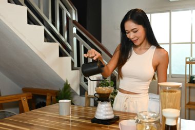 Bir kadın kahve yapıyor. Kahveyi fincana dökerken gülümsüyor...