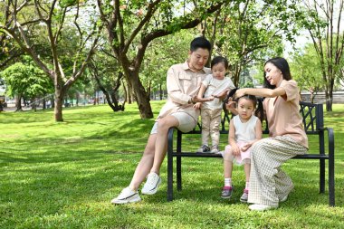 Dört kişilik bir aile bir bankta oturur ve birlikte vakit geçirmenin keyfini çıkarırlar..