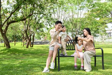 Dört kişilik bir aile bir bankta oturur ve birlikte vakit geçirmenin keyfini çıkarırlar...