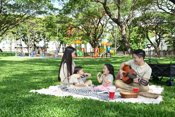 Dört kişilik bir aile parkta piknik yapıyor. Çocuklar yemek yerken adam gitar çalıyordu. Sahne mutlu ve rahat..