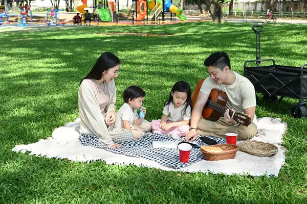 Dört kişilik bir aile parkta piknik yapıyor. Çocuklar yemek yerken adam gitar çalıyordu. Sahne mutlu ve rahat...