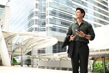 Bir adam elinde cep telefonuyla kaldırımda yürüyor..