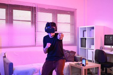 Sanal gerçeklik ortamında boks yaparak genç Asyalı atletizm sporcusu, modern evdeki teknoloji ve uygunluğu birleştiriyor...