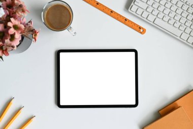 Tablet, kahve ve kırtasiyeli minimalist beyaz ofis masası..